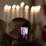 Obama at the earlier holiday reception, obscured by raised smart fone cameras