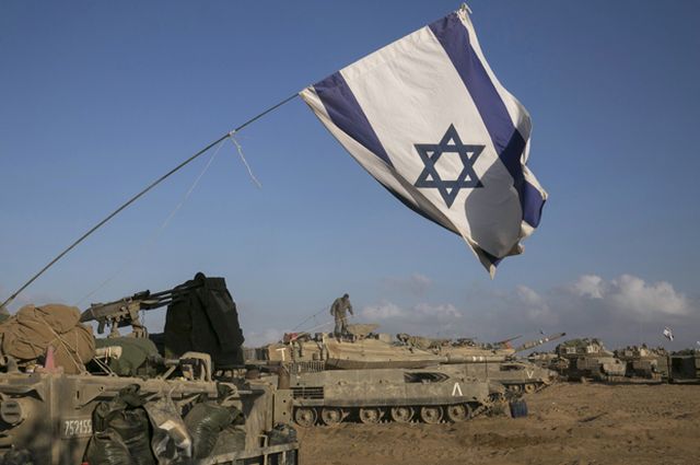 Israeli tanks and armoured personnel carriers are seen at a staging area outside the central Gaza Strip